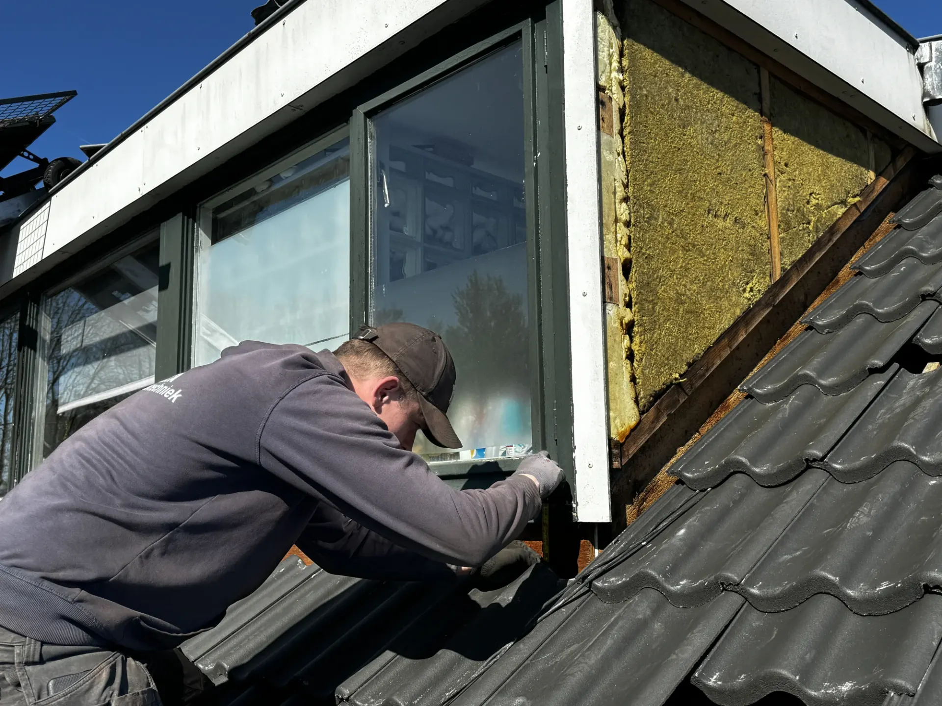 Dakdekkers werken aan een dakraam in een pannendak